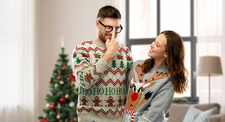 Image showing happy couple in christmas ugly sweaters at home