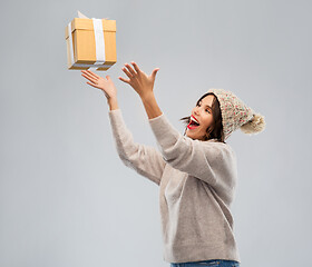 Image showing young woman in winter hat catching gift box