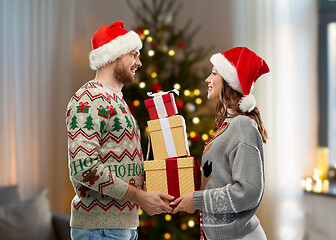 Image showing couple in christmas sweaters with gifts at home