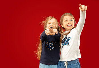 Image showing Beautiful emotional little girls isolated on red background