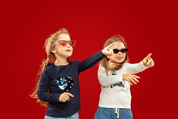 Image showing Beautiful emotional little girls isolated on red background