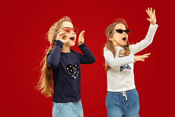 Image showing Beautiful emotional little girls isolated on red background