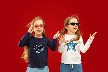 Image showing Beautiful emotional little girls isolated on red background