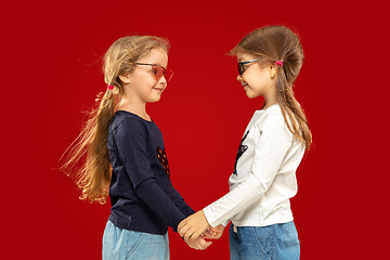 Image showing Beautiful emotional little girls isolated on red background