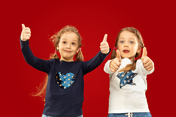 Image showing Beautiful emotional little girls isolated on red background