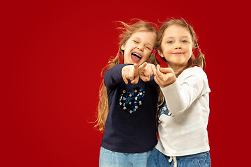 Image showing Beautiful emotional little girls isolated on red background