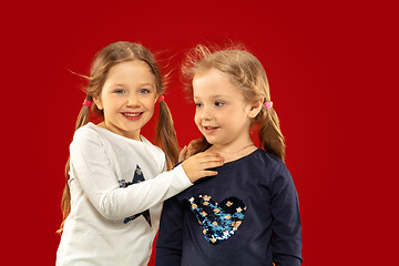 Image showing Beautiful emotional little girls isolated on red background