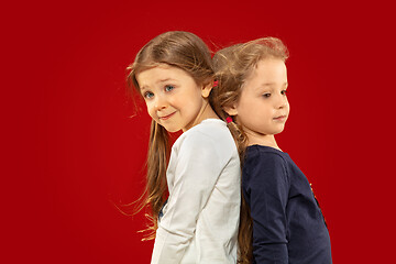 Image showing Beautiful emotional little girls isolated on red background