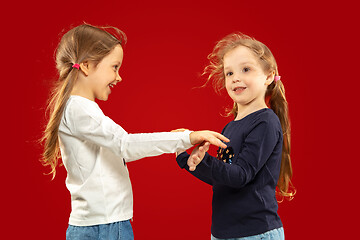 Image showing Beautiful emotional little girls isolated on red background