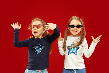 Image showing Beautiful emotional little girls isolated on red background