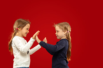 Image showing Beautiful emotional little girls isolated on red background