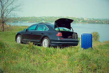 Image showing View of modern black car and suitcase on the river\'s side