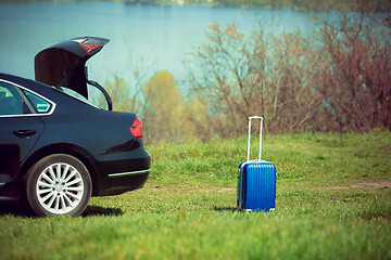 Image showing View of modern black car and suitcase on the river\'s side