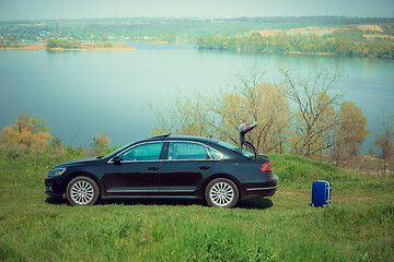 Image showing View of modern black car and suitcase on the river\'s side