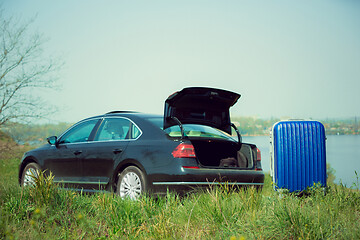 Image showing View of modern black car and suitcase on the river\'s side