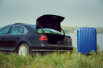 Image showing View of modern black car and suitcase on the river\'s side