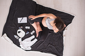 Image showing top view of pregnant woman checking list of baby clothes