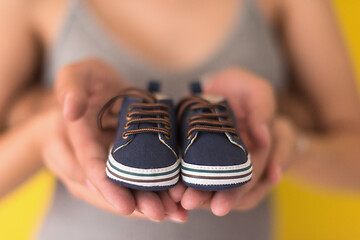Image showing couple holding newborn baby shoes