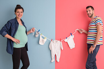 Image showing young couple holding baby bodysuits