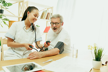 Image showing The visiting nurse taking care of senior man