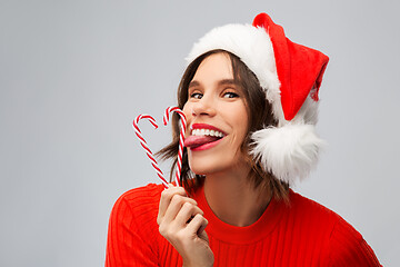 Image showing woman in santa hat licks candy canes on christmas