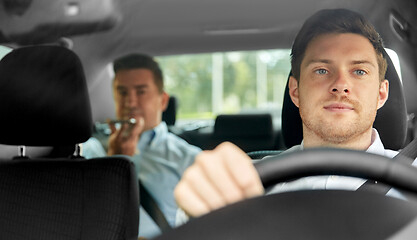 Image showing male taxi driver driving car with passenger