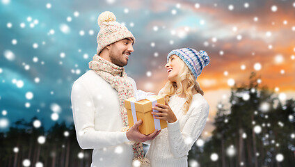 Image showing smiling couple in winter clothes with gift box