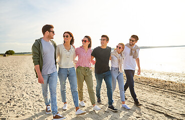 Image showing happy friends walking along summer beach