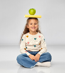 Image showing little girl with book and apple sitting on floor