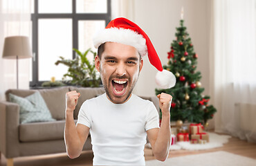 Image showing man in santa hat celebrating victory at home