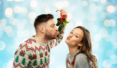 Image showing happy couple kissing under mistletoe on christmas