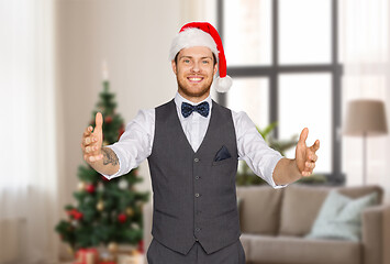 Image showing happy man in santa hat holding something imaginary