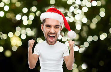 Image showing man in santa hat celebrating victory at home