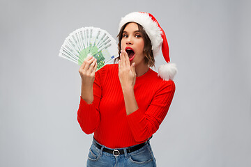 Image showing surprised woman in santa hat with money