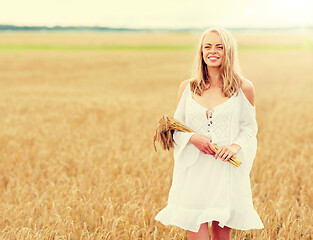 Image showing happy young woman with spikelets on cereal field