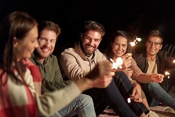 Image showing happy friends with sparklers on beach at night