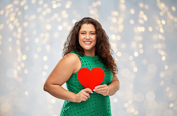 Image showing happy woman holding red heart over lights