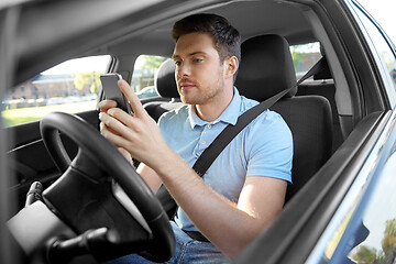 Image showing man driving car and using smartphone