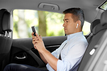 Image showing passenger with earphones and cellphone in taxi car