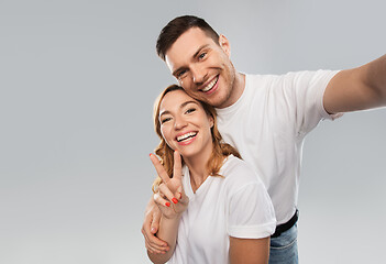 Image showing happy couple in white t-shirts taking selfie