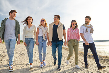 Image showing happy friends walking along summer beach