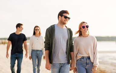 Image showing happy friends walking along summer beach