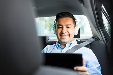 Image showing passenger with headphones using tablet pc in car