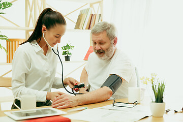 Image showing The visiting nurse taking care of senior man