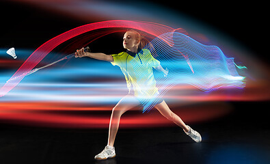 Image showing Young girl playing badminton over dark background