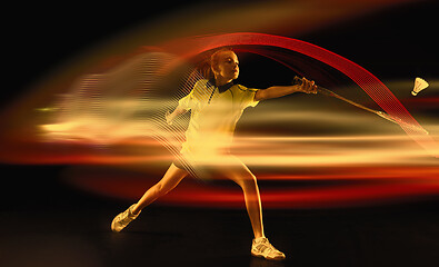 Image showing Young girl playing badminton over dark background