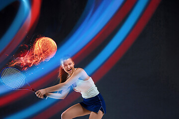 Image showing Full length portrait of young woman playing tennis on dark studio background