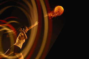 Image showing Full length portrait of young woman playing tennis on dark studio background