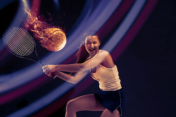Image showing Full length portrait of young woman playing tennis on dark studio background