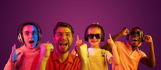 Image showing Beautiful male and female models in neon light isolated on purple studio background